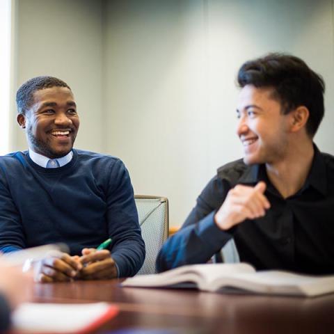 UNH Graduate students talking at table with textbook